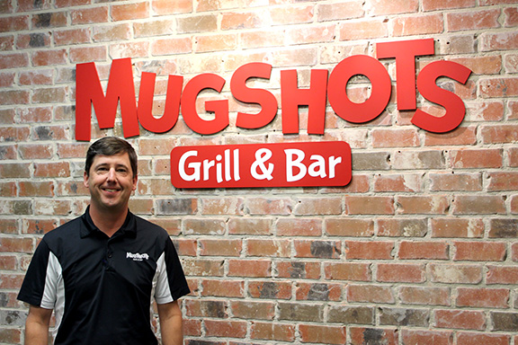 Ron Savell in front of a Mugshots sign