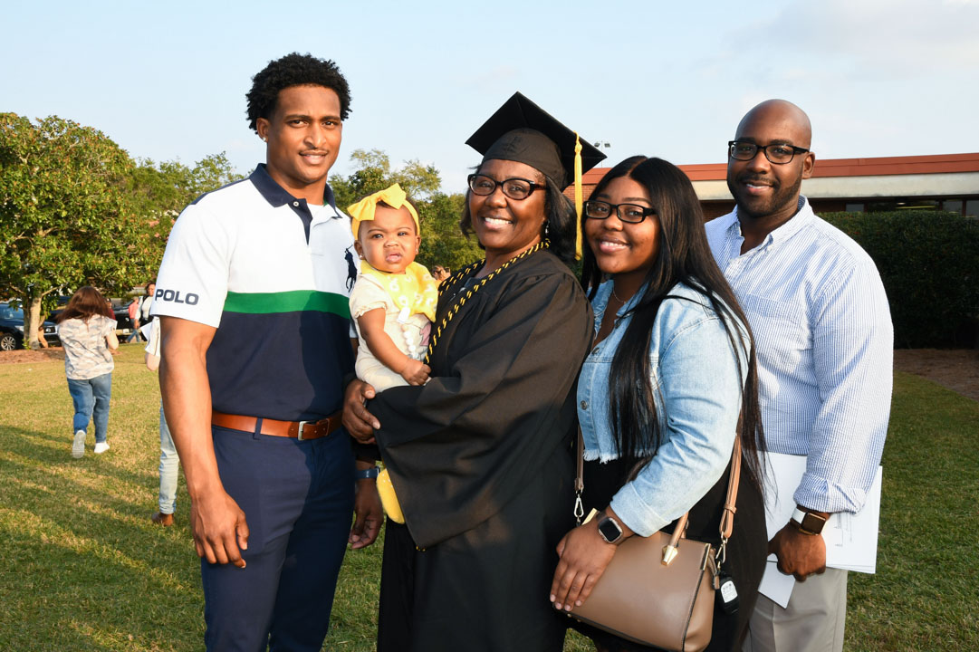 Graduate poses with family outside of Reed Green Coloseum after commencement. 