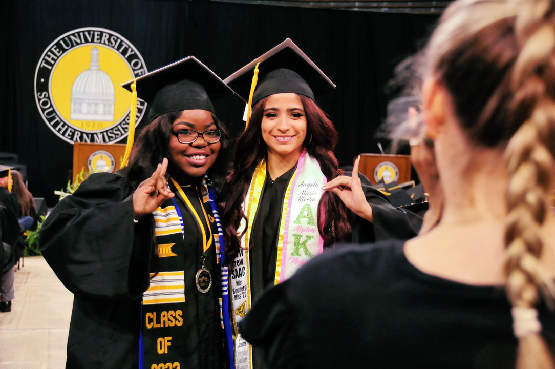 Graduates smile while waiting to recieve their diplomas