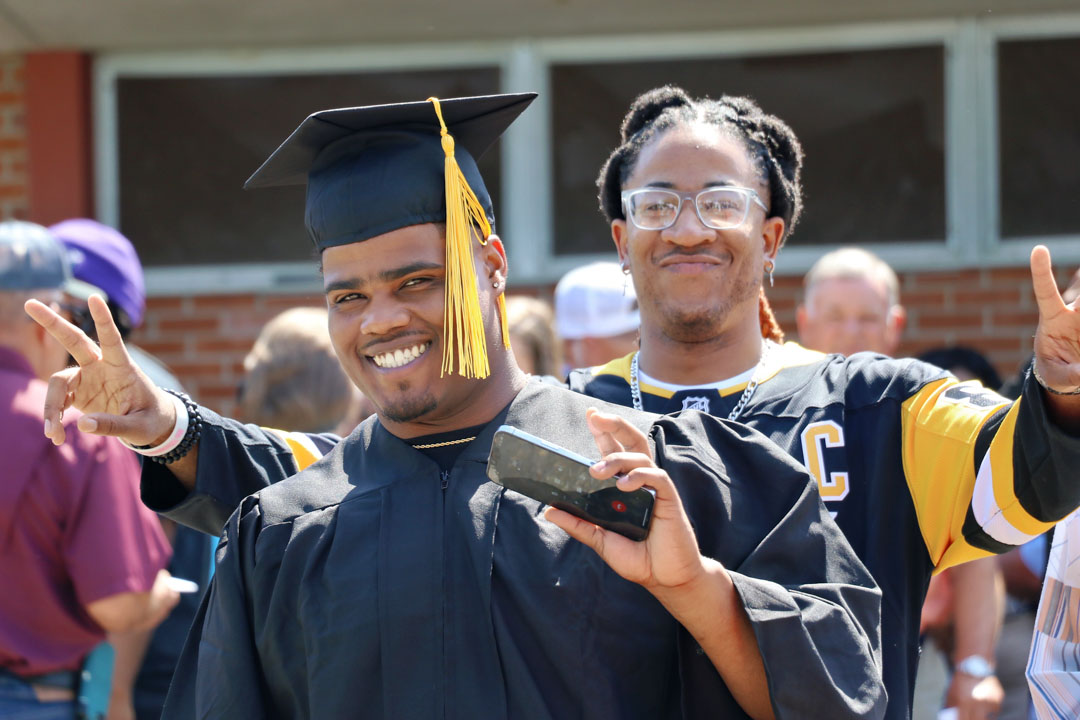 Graduate poses outside of Reed Green Coloseum 